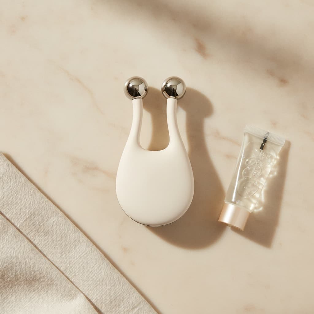 Appareil de tonification faciale non marqué à deux têtes métalliques et tube de gel conducteur sur marbre ivoire